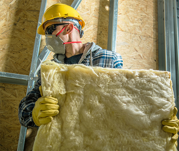 Roofer with a mask carrying glass wool
