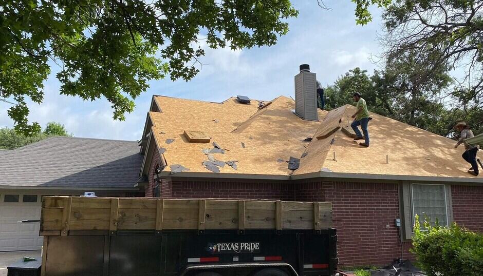 roofers tearing off the shingles and underlayment for a roof replacement