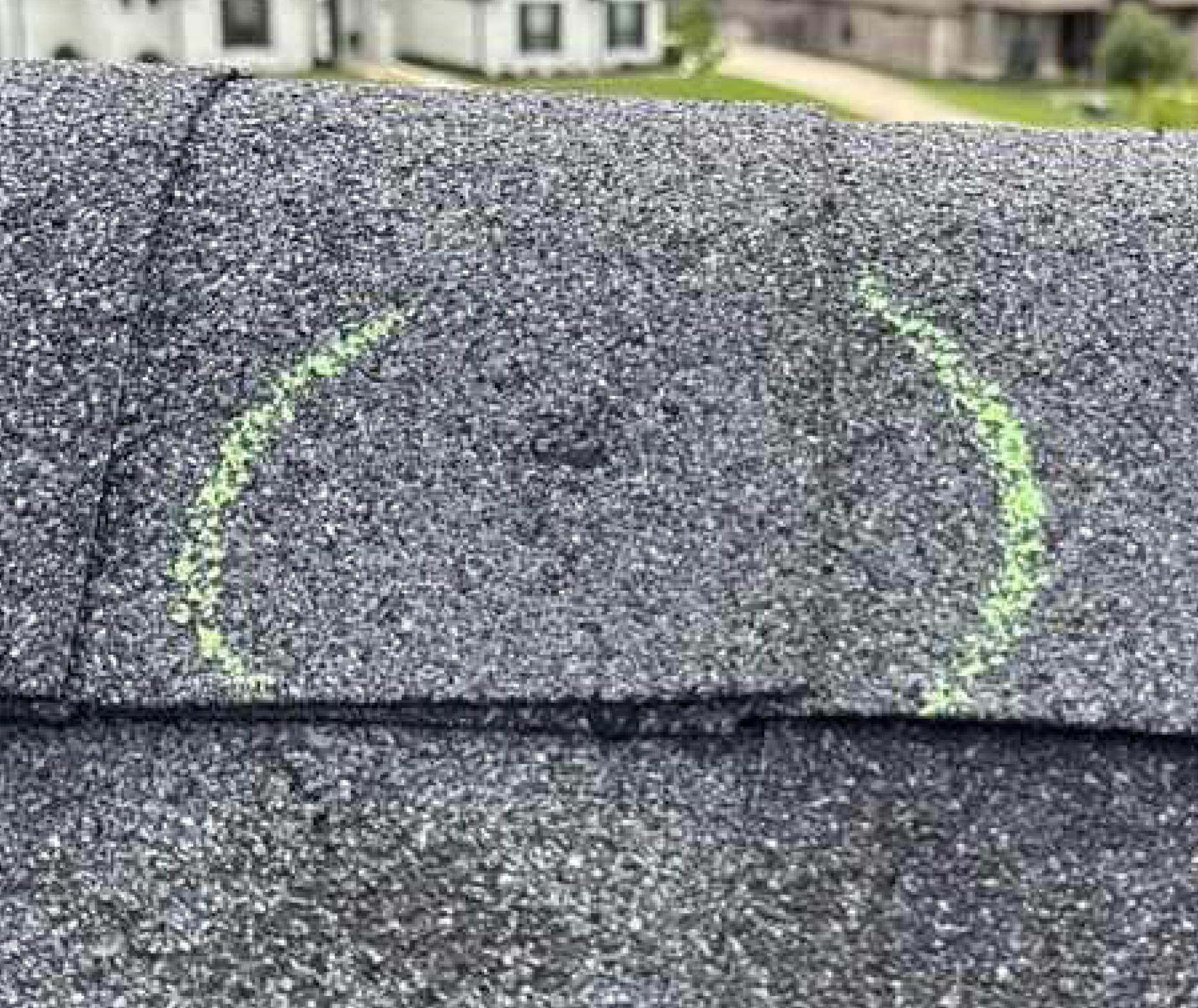 Close-up of asphalt shingles showing hail impact damage and bruising